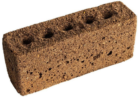 Ein rechteckiger brauner Lehmziegel mit rauer Textur und fünf gleichmäßig auf der Oberseite verteilten kreisförmigen Löchern, perfekt für die Unterbringung von Véritables Organic Samen aus der Lingot Grow Anything-Reihe in einem Indoor-Garten. Der Ziegel ist vor einem weißen Hintergrund abgebildet.