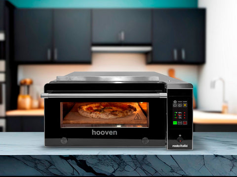 Der Resto Italia Hooven 341 Elektro Pizzaofen (Digital) mit Sorrento-Keramiksteinen backt eine neapolitanische Pizza, auf einer modernen Marmor-Küchentheke mit schwarzen Schränken und Utensilien im Hintergrund.