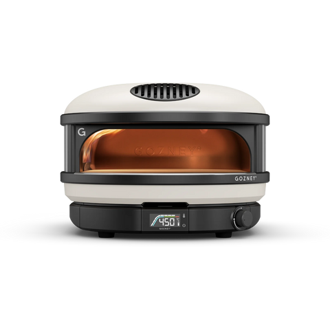 Un four à pizza à gaz Gozney Arc XL élégant et moderne en noir et blanc avec un affichage numérique de la température de 450 °F sur le devant. Le four dispose d'une grande fenêtre frontale éclairée en orange qui met en valeur l'espace de cuisson intérieur. Le nom de la marque "Gozney" est visible, parfait pour cuire des pizzas jusqu'à 16 pouces.