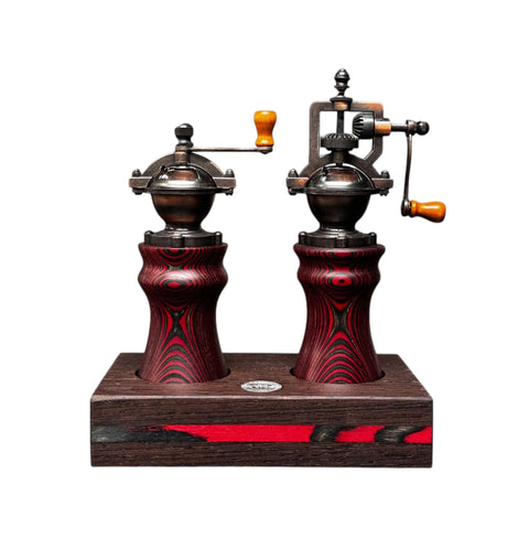 Zwei manuelle Kaffeemühlen im Vintage-Stil mit Holzgriffen und verzierten Sockeln auf einem Räucherwerk-Ständer weisen ein rot-schwarzes Wirbeldesign auf, das an das elegante Metallic-Finish des Bundle Pfeffermühle & Salzmühle mit Sockel – RED DEVIL von Jungo Design erinnert.