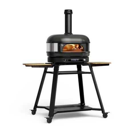 Der Gozney Dome Gen 2 Pizzaofen - Hybrid Brennstoffsystem von Gozney verfügt über einen Schornstein, eine schwarze Oberfläche, einen holzbefeuerten Innenraum, einen Metallständer mit klappbaren Holzböden und vier Rädern - ideal für Ihre Outdoor Küche.