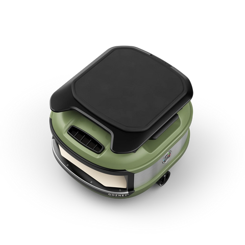 Luftaufnahme der Gozney Ablagefläche - Roof Rack für Tread, einem grünen und schwarzen tragbaren Outdoor-Pizzaofen mit kompaktem, abgerundetem Design, der perfekt für jede Outdoor-Küche ist. Er verfügt über sichtbare Lüftungsschlitze und einen stabilen Griff an der Vorderseite.