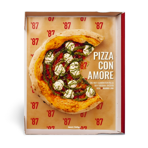 Eine Pizza mit Tomatenscheiben, Mozzarella und Kräutern liegt in einer offenen Schachtel. Die Innenseite der Schachtel ist mit dem roten Schriftzug „'87“ verziert, während auf der rechten Seite elegant die Worte „Pizza con Amore“ prangen. Dieses geschmackvolle Meisterwerk fängt den wahren Geist neapolitanischer Pizzas ein, die mit Liebe und Sorgfalt hergestellt werden, ähnlich wie die Angebote aus Ava Verlagsauslieferungsbuch Pizza con Amore.