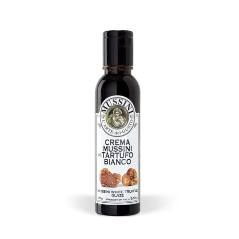 Eine 150-ml-Flasche Crema Balsamica – Gourmet Weißer Trüffel von Mussini ist vor einem weißen Hintergrund zu sehen. Das Etikett enthält einen Text auf Italienisch und Bilder von weißen Trüffeln, während die Flasche mit einem schwarzen Deckel versehen ist.