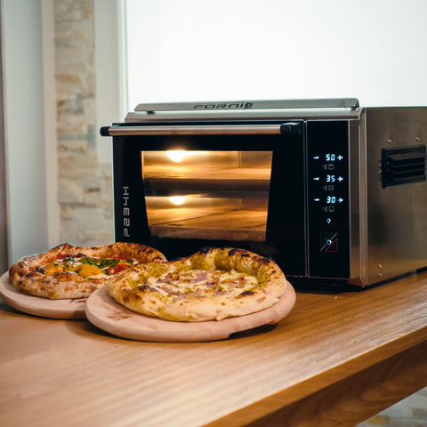 Zwei neapolitanische Pizzen liegen auf Holzbrettern neben einem Pizzaofen. Die Digitalanzeige des Effeuno Pizzaofens P234H PRO 509°C zeigt die Temperatur präzise an. Mit verschiedenen Zutaten belegt, passen die Pizzen perfekt zu den hellen Holzoberflächen der modernen Küche.