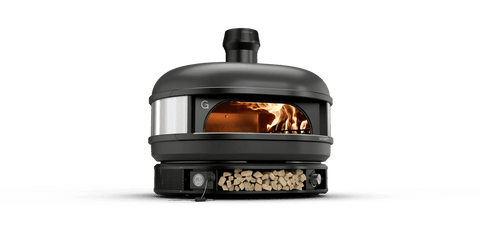 Ein eleganter, schwarzer Pizzaofen für den Außenbereich mit gewölbter Oberseite und Kamin, mit einer Öffnung an der Vorderseite und sichtbaren Flammen im Inneren. Darunter befindet sich ein Lagerraum für Holzscheite. Dieses Design des Gozney Dome Pizzaofens (Multi-Fuel Gas/Holz) Off Black (Limited Edition) kombiniert moderne und traditionelle Elemente und ist perfekt für alle, die gerne mit Holz kochen wie Profiköche.