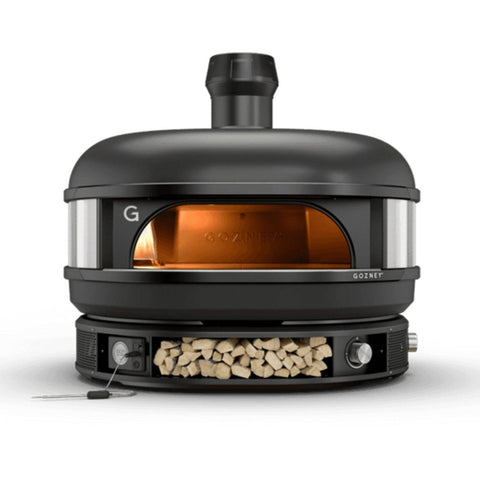 Ein eleganter schwarzer Gozney Dome Pizzaofen (Multi-Fuel Gas/Holz) Off Black (Limited Edition) mit abgerundeter Oberseite, einem Kamin und einer offenen Tür, die einen bernsteinfarben beleuchteten Innenraum freigibt. Der Ofen verfügt unten über ein Holzfach, das mit ordentlich gestapelten Holzscheiten gefüllt ist. Dieser Ofen ist perfekt für Kochen mit Holz und wird von Profiköchen bevorzugt. Das Gozney-Logo ist auf der Vorderseite sichtbar.