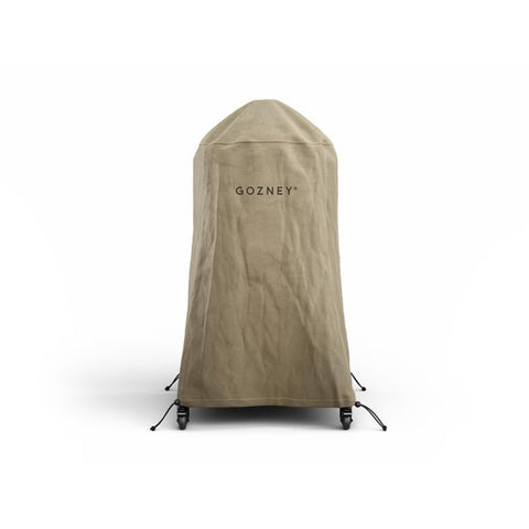 Une housse Gozney Dome Lang marron clair, résistante aux intempéries, se place sur un four à pizza Gozney Dome. Le mot "GOZNEY" est imprimé en noir sur le devant du couvercle. La couverture est dotée de fixations à sangles réglables dans les coins inférieurs, qui se fixent aux pieds du four.