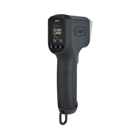 Un thermomètre infrarouge numérique portable noir 2024 de Ooni avec un écran LCD affichant une température de 500 °F. L'appareil dispose d'une poignée structurée et d'un œillet de suspension sur la partie inférieure. Le nom de la marque "Ooni" est visible sur l'écran et sur le côté du thermomètre, parfait pour une utilisation avec les fours à pizza Ooni.