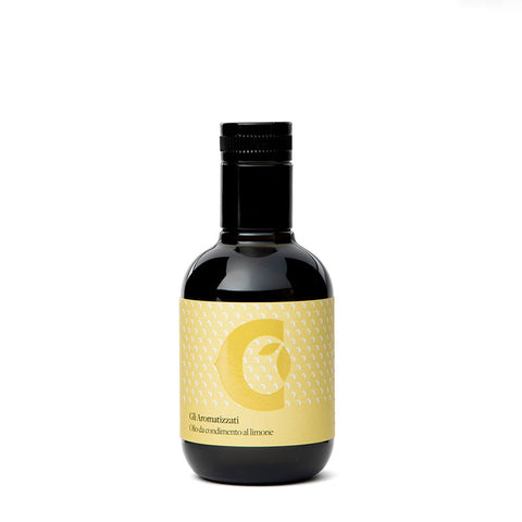 Une bouteille de couleur sombre avec un bouchon noir porte une étiquette jaune avec un design minimaliste et la lettre "C". L'étiquette indique en italien "Huile d'olive extra vierge aromatisée au citron (100 ml)", ce qui indique qu'il s'agit d'une huile aromatisée au goût de citron, produite à partir d'huile d'olive extra vierge. Le nom de la marque est Ciccolella.