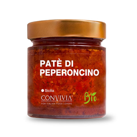Die „Bio Chilipastete Convivia“ von Convivia stammt aus Sizilien und ist ein feuriges Gewürz, das italienische Feinschmecker lieben. Auf dem Etikett steht prominent „Bio“, was auf die Bio-Zutaten hinweist, und obendrauf befindet sich ein kupferfarbener Deckel, der die leuchtende Bio-Chilipastete enthält.