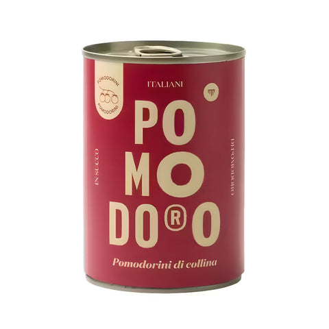 Eine rote Dose mit einem beigen Etikett, auf dem in großen Buchstaben „POMODORO“ steht. Darunter steht „Pomodorini Di Collina“, was die Cherrytomaten von süditalienischen Hügeln hervorhebt. Die Dose ist mit einem Metalldeckel verschlossen und auf dem Etikett befinden sich kleine runde Logos und andere Texte in italienischer Sprache. Der Markenname „Mammafiore“ ist auf der Verpackung deutlich sichtbar.