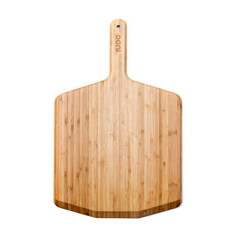 La pelle à pizza Ooni Wood 14" présente une surface rectangulaire lisse avec des bords arrondis. La poignée marquée du nom de la marque "Ooni" dispose d'un petit trou pour la suspendre. Elle est conçue pour le Ooni Pro et dispose d'une surface résistante à l'humidité. Les veines du bois visibles lui confèrent un aspect naturel et rustique.