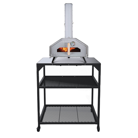 Ein silberner Ooni-Pizzaofen mit Kamin steht auf einem schwarzen Ooni Modultisch Gross von Ooni, der mit zwei Ablagen ausgestattet ist und sich ideal für jede Outdoor-Küche eignet. Im Inneren des Ofens glüht das Feuer, und an der Vorderseite befindet sich eine Temperaturanzeige.