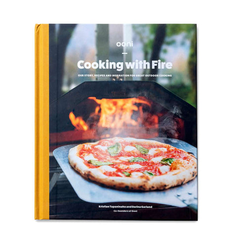 Le livre de cuisine intitulé "Livre de cuisine Ooni : Cuisiner avec le feu" de Kristian Tapaninaho et Darina Garland, les cofondateurs d'Ooni, a été publié par Ava Verlagsauslieferung. Sur la couverture, on voit une pizza cuite dans un four à bois. En arrière-plan, on peut voir des flammes dans le four, ce qui met en valeur l'art de cuisiner en plein air dans leur livre de cuisine Ooni.