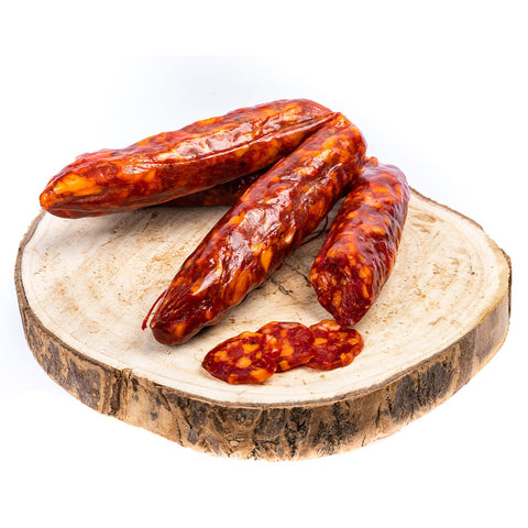 Eine Auswahl mehrerer Salsiccia Salami BIO (Scharf), arrangiert auf einem Holzbrett, mit zwei kleinen Salamischeiben im Vordergrund. Die Madeo-Salami hat eine satte, tiefrotbraune Farbe mit sichtbarer Fettmarmorierung, die an pikantes, gepökeltes Fleisch erinnert. Perfekt für alle, die Fleischspezialitäten lieben.