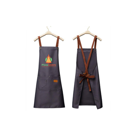 Due grembiuli neri Pizzalovers appesi alle grucce. Il grembiule anteriore, Pizzalovers Pizzaiolo Apron, presenta un logo a fiamma viva e il testo "Pizza Lovers" e ha due pratiche tasche. Il grembiule posteriore è dotato di cinghie in pelle marrone regolabili che si incrociano e si annodano in vita, rendendolo la scelta ideale per qualsiasi pizzaiolo in una pizzeria.