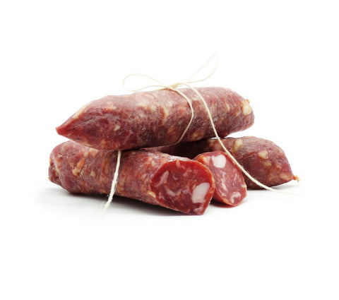 Drei Stücke Salsiccia Salami BIO (Mild) der Marke Madeo liegen auf einem weißen Untergrund. Die aus Schweineschulter und Fenchelsamen hergestellten Würste sind mit einer weißen Schnur zusammengebunden, ein Stück ist aufgeschnitten und gibt den Blick auf das marmorierte Innere aus Fleisch und Fett frei.