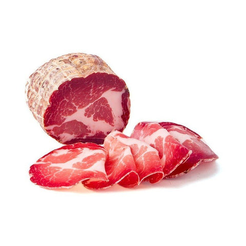 Una spessa fetta di Capocollo Calabrese Mite (Coppa) Madeo - 700 g in un unico pezzo, con un disegno marmorizzato di carne magra e grassa, parzialmente tagliata in pezzi sottili e teneri disposti sul davanti. Le fette hanno un colore rosso vivo con strisce bianche, che ricordano i tradizionali antipasti mediterranei, su sfondo bianco.