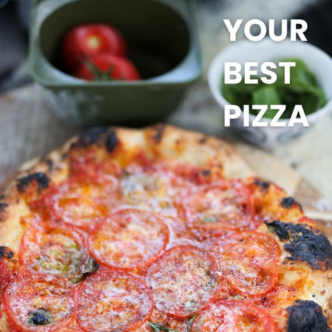 Eine Nahaufnahme einer frisch gebackenen Pizza mit Tomatenscheiben, Käse und Kräutern. Im Hintergrund sind Schüsseln mit ganzen Tomaten und frischen Basilikumblättern sowie Babadoh Silikon BIG Pizzateig und Zutatenbehälter 3er-Set zu sehen. Auf der rechten Seite des Bildes steht in fetten weißen Buchstaben der Text „Your Best Pizza“.