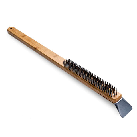 Une brosse à four à pizza Ooni à long manche avec un manche en bois et des poils noirs. Le manche est muni d'un trou à l'extrémité pour le suspendre. À l'extrémité opposée aux poils se trouve un grattoir en acier inoxydable destiné au nettoyage des barbecues. Le fond est blanc.