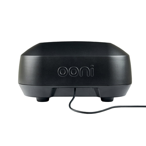 Ein schwarzer Ooni Volt 12 Elektro-Pizzaofen, von hinten gezeigt, zeigt ein schlankes und modernes Design mit einem glatten, abgerundeten Äußeren. Das Wort „Ooni“ sticht in Weiß deutlich auf der Rückseite hervor. Ein Netzkabel verläuft von der Unterseite und kann an eine 230-V-Steckdose angeschlossen werden, um drinnen perfekte neapolitanische Pizzen zuzubereiten.