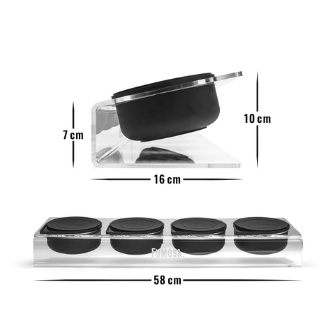 Die FUMOSA Pizzastation POMPEY besteht aus einem transparenten Ständer, auf dem vier schwarze, runde Behälter mit Deckel aus lebensmittelechtem Silikon stehen. Der Ständer ist 16 cm lang, 10 cm hoch und an der Basis 7 cm breit, wobei die Behälteranordnung einen Abstand von 58 cm hat. Der Markenname „Fumosa“ ist deutlich auf dem Ständer aufgedruckt.