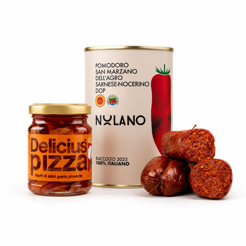 Ein Glas mit in Scheiben geschnittenen scharfen Paprikaschoten, eine Dose San-Marzano-Tomaten und zwei Stück scharfe Wurst, von denen eines aufgeschnitten ist – alles auf weißem Hintergrund angerichtet.