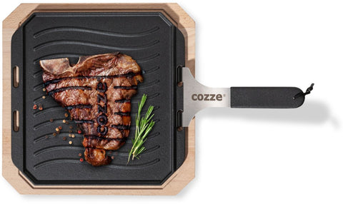 Ein perfekt gegrilltes Steak liegt auf der Cozze Gusseisen-Wendepfanne mit Untersetzer 330x330mm von Cozze, verziert mit Rosmarin und Pfefferkörnern - das ideale Zubehör für den Pizzaofen.