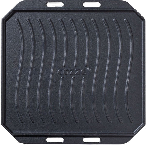 Die Cozze Gusseisen-Wendepfanne mit Untersetzer 330x330mm ist eine schwarze, quadratische Grillplatte aus Gusseisen mit Rillen und zwei gegenüberliegenden Griffen. In der Mitte ist "Cozze" eingeprägt - perfektes Pizzaofen-Zubehör für Ihre Küche.