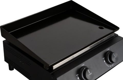 Eine Nahaufnahme der Cozze G-400 Plancha Gas 50mbar - CH-Regler von Cozze, die zwei Bedienknöpfe, eine glatte Kochfläche und ein kleines Abflussloch in der Ecke zeigt.