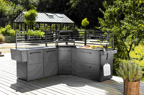 Moderne Außenküche auf einer Holzterrasse mit schlichten grauen Schränken, einem Grill und Cozze Elements Haken für Rückwand 5er Pack für Utensilien; Gewächshaus und Garten sind im Hintergrund zu sehen.