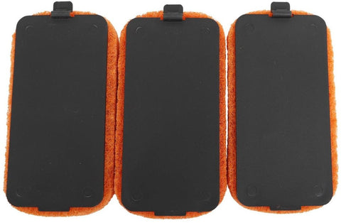Drei schwarze, rechteckige Cozze Scheuerschwamm-Reinigungspads mit orangefarbenen Rändern, die jeweils mit einem kleinen schwarzen Clip versehen sind, werden nebeneinander auf weißem Hintergrund gezeigt. Sie werden im 3er-Pack von Cozze verkauft und sind ideal für die effektive Reinigung von Oberflächen.