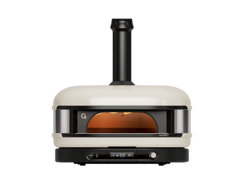 Ein cremefarbener Gozney Dome Gen 2 Pizzaofen - Hybrid Brennstoffsystem von Gozney mit Schornstein, Glasfrontfenster und Bedienknöpfen wird von vorne auf einem schlichten weißen Hintergrund gezeigt.