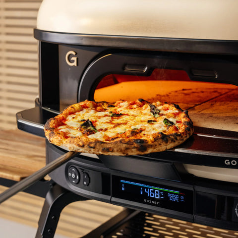 Eine frisch gebackene Pizza wird aus der Gozney Ofensims & Frontablage für Dome (Gen 2) von Gozney entnommen, deren Digitalanzeige eine Temperatur von 468°F anzeigt.