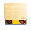 Ein rechteckiger Bambusdeckel mit der Gravur „Babadah“ bedeckt teilweise die Babadoh Box – Steel von Babadoh, unterteilt in drei Abschnitte zur Aufbewahrung von Chicken Wings, einer Box mit gelbem Deckel und Kirschtomaten – ideal für Pizza-Liebhaber bei jedem Teig-Abenteuer.
