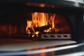 Das Bild zeigt das Innere eines holzbefeuerten Gozney° Dome mit hellen, orangefarbenen Flammen, die um Holzstücke tanzen. Der Ofen verfügt über einen metallenen Gozney Dome Holz-Brennkorb, der das Holz hält, während das Feuer sichtbar intensiv ist, was darauf hindeutet, dass es voll entzündet ist und hohe Hitze erzeugt. Perfekt für jeden Pizzaofen-Liebhaber.