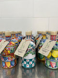 Mehrere bunte Keramikflaschen mit Korken und braunen Papieranhängern sind auf einer glänzenden Oberfläche angeordnet. Die handgefertigten Keramikflaschen mit Cunzatillu Olivenöl weisen komplizierte, lebendige Designs auf, darunter florale und geometrische Muster, die die sizilianische Tradition widerspiegeln, und scheinen Cunzatillu-Behälter zu sein.